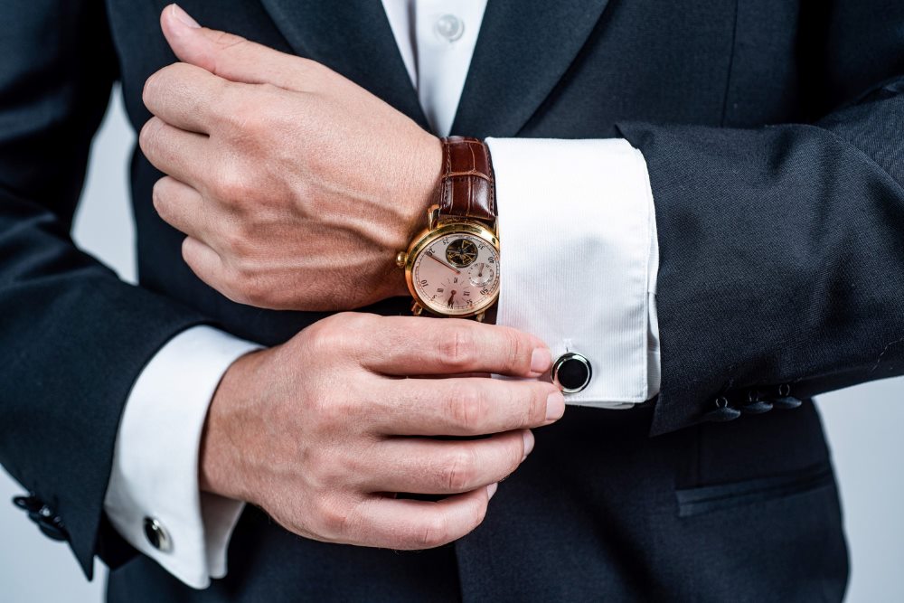 Las mejores marcas de relojes de lujo 1 Hombre acomodando puños de su traje con un reloj de lujo en su muñeca